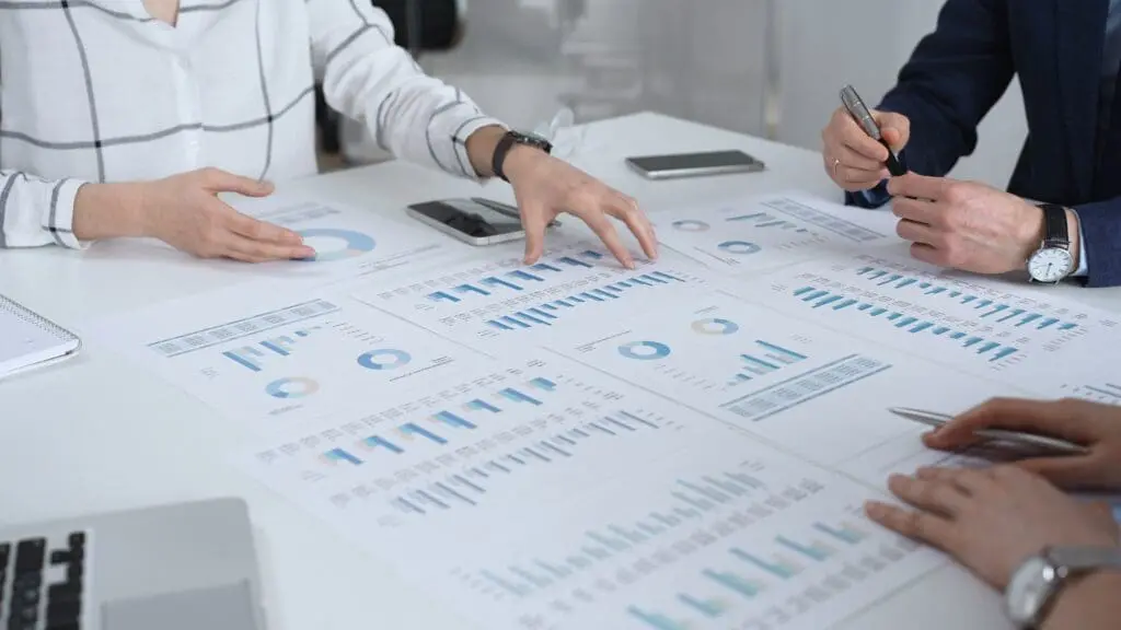 Business team in a conference room reviewing financial reports, charts and graphs across the table, collaborating on strategy